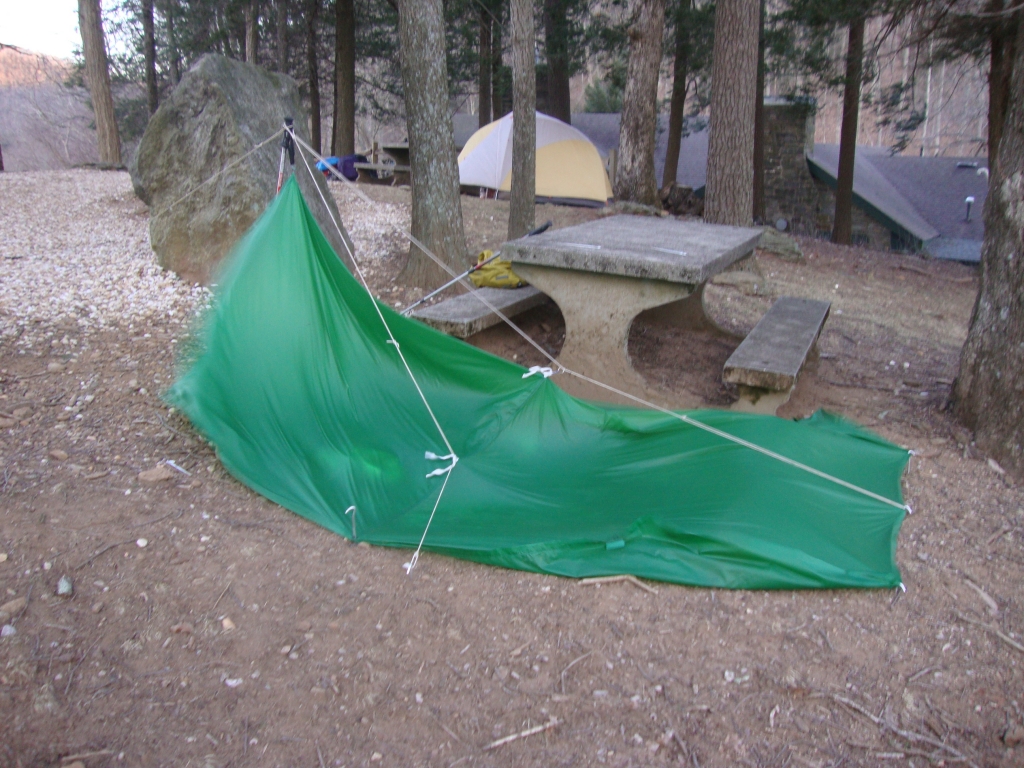 At a Mountain Crossings employee's suggestion, I erected my tarp, in the dark, on the rocky ground behind the outfitter's and crawled in, still wearing my hiking clothes, exhausted and grateful for protection from the fierce wind. Gusts of 60 to 70 mph sounded like a freight train bearing down on me, and the temperature reached 14F. This 8 AM photo shows the wind-flattened tarp, with one front stake pulled out; I was unable to drive it back in during the night. 