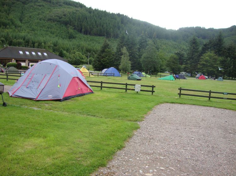 Glen Nevis Campground, 6:00 PM. I hung my mosquito net but midges crawled in and out through its mesh. Several campers were motorcyclists, but the man with the low green tent to my left was a solitary hiker. The building contained nice laundry and bathroom facilities.